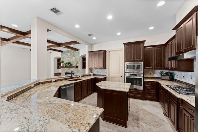 kitchen featuring light stone countertops, coffered ceiling, beamed ceiling, a spacious island, and appliances with stainless steel finishes