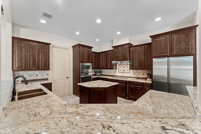 kitchen featuring light stone countertops, dark brown cabinetry, stainless steel appliances, and sink