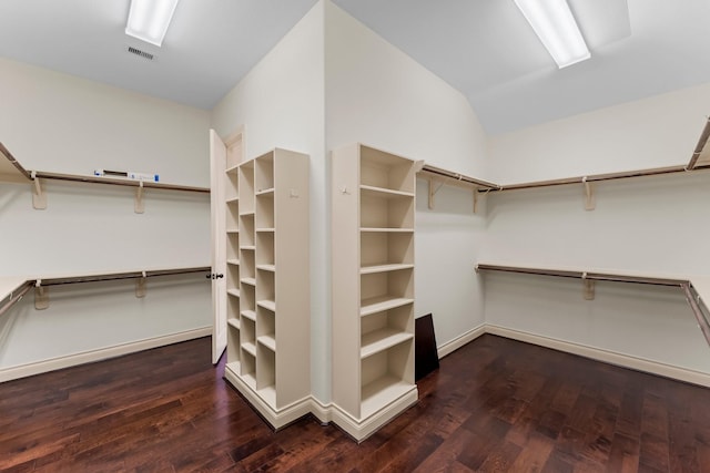 walk in closet with dark hardwood / wood-style floors and vaulted ceiling