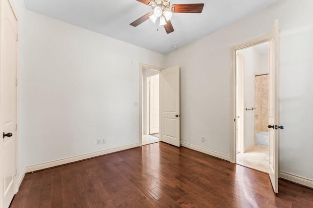 unfurnished bedroom featuring ensuite bath, ceiling fan, and dark wood-type flooring