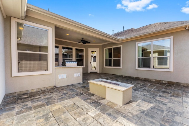 view of patio with area for grilling, ceiling fan, an outdoor fire pit, and exterior kitchen