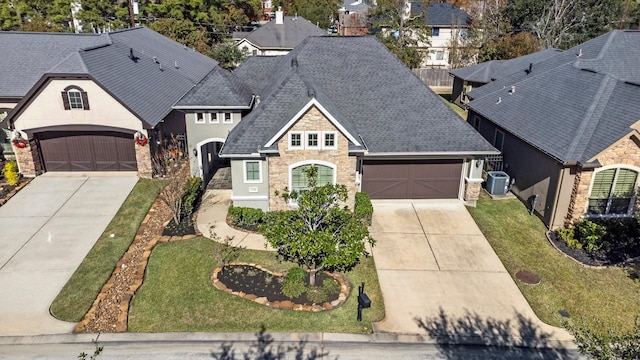 view of front of house with central AC unit, a front lawn, and a garage