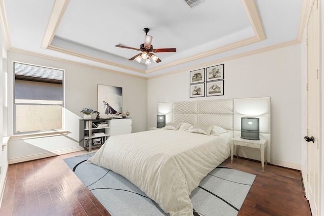 bedroom with ceiling fan, ornamental molding, dark wood-type flooring, and a tray ceiling