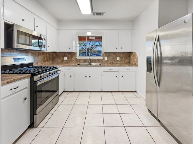 kitchen with white cabinets, decorative backsplash, stainless steel appliances, and sink