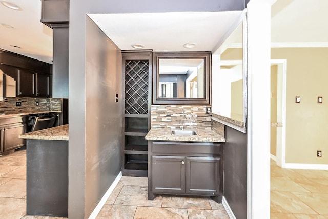 kitchen featuring sink, ornamental molding, light stone countertops, tasteful backsplash, and dark brown cabinets