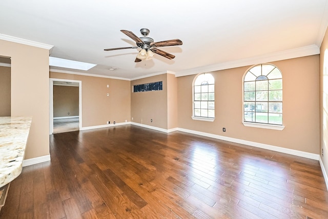 unfurnished room featuring ceiling fan, ornamental molding, dark wood-type flooring, and a skylight