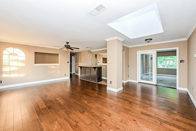 unfurnished living room with a skylight, ceiling fan, dark hardwood / wood-style flooring, and ornamental molding