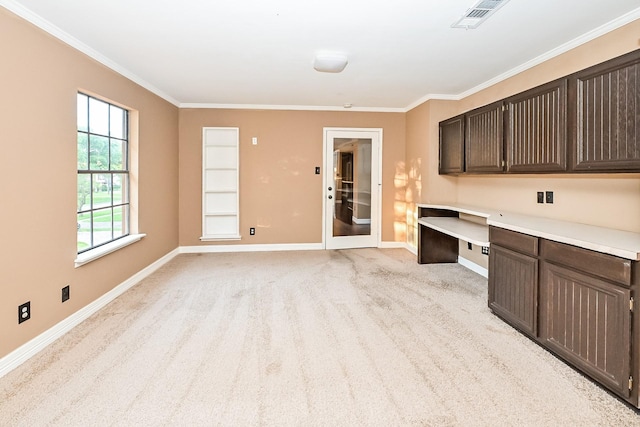 interior space featuring dark brown cabinets, built in desk, light colored carpet, and crown molding