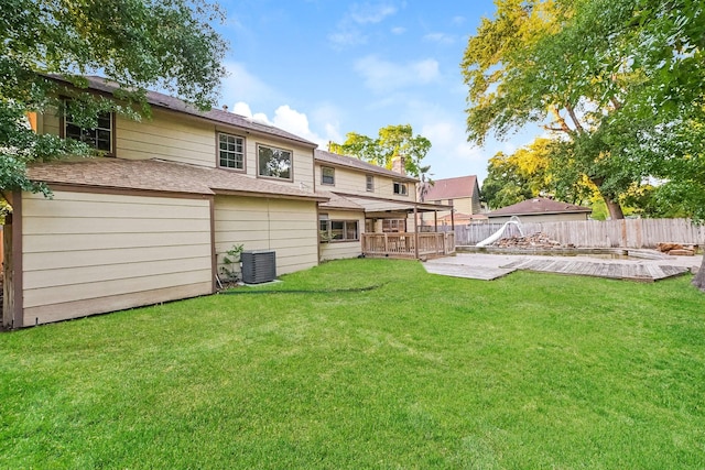 rear view of property with central air condition unit, a deck, and a lawn