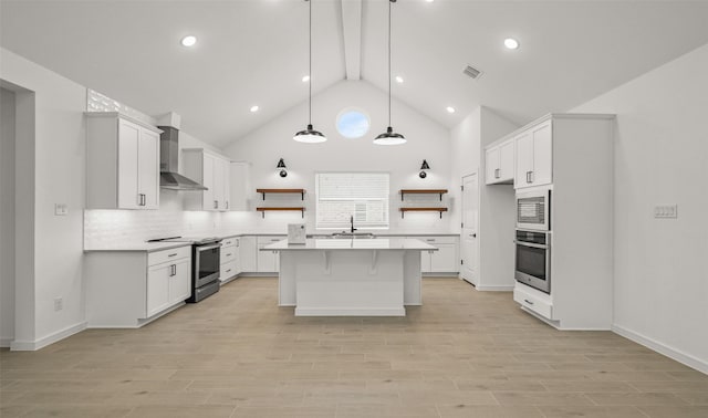 kitchen featuring pendant lighting, wall chimney range hood, appliances with stainless steel finishes, white cabinetry, and a center island