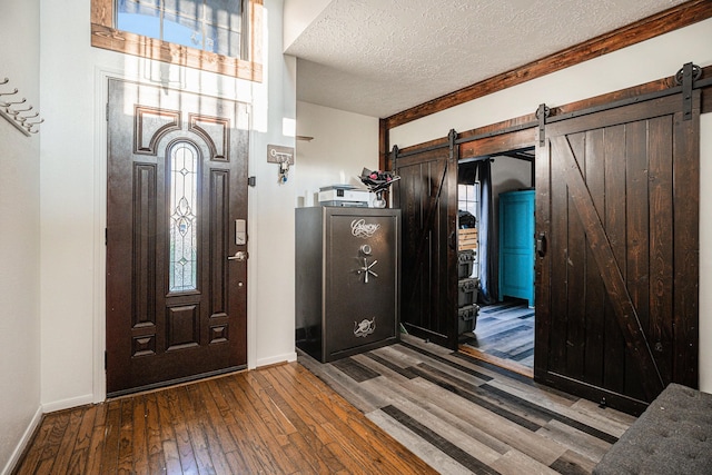 entryway featuring a barn door, wood-type flooring, and a textured ceiling