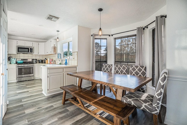 dining space with sink, a textured ceiling, and light wood-type flooring