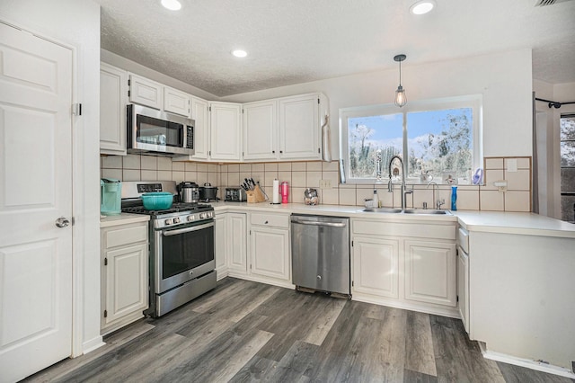 kitchen with dark hardwood / wood-style flooring, stainless steel appliances, sink, decorative light fixtures, and white cabinetry