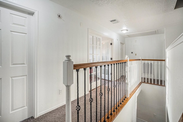 hall featuring dark carpet and a textured ceiling