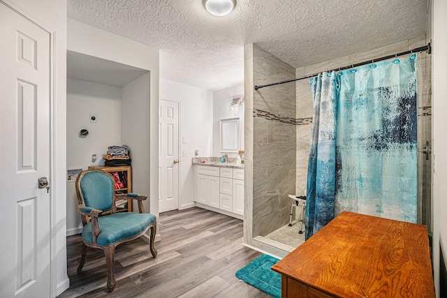 bathroom with a shower with shower curtain, wood-type flooring, vanity, and a textured ceiling