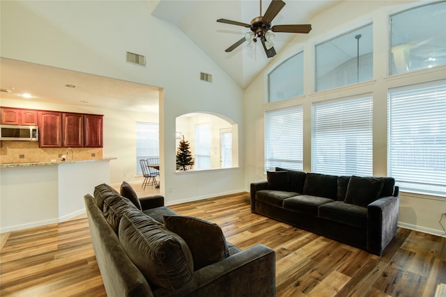 living room with ceiling fan, high vaulted ceiling, and wood-type flooring