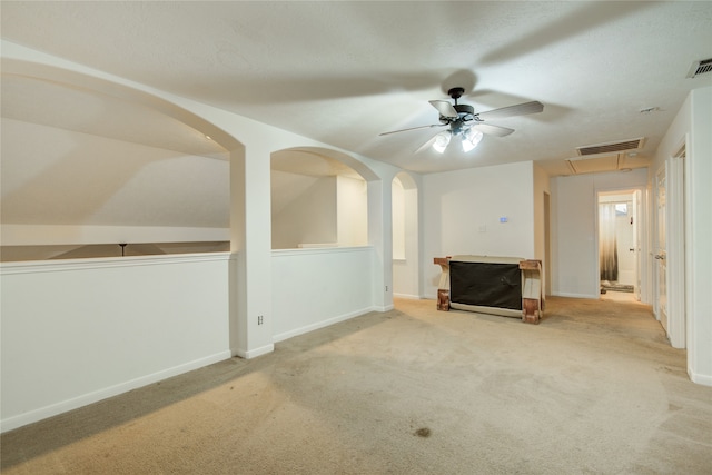 unfurnished living room featuring ceiling fan, light colored carpet, and vaulted ceiling