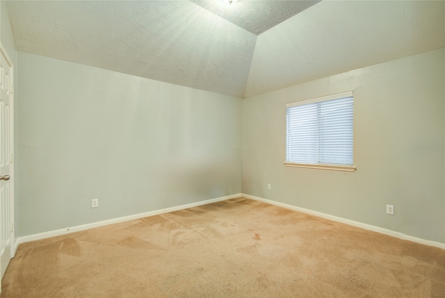 carpeted spare room with a textured ceiling and vaulted ceiling