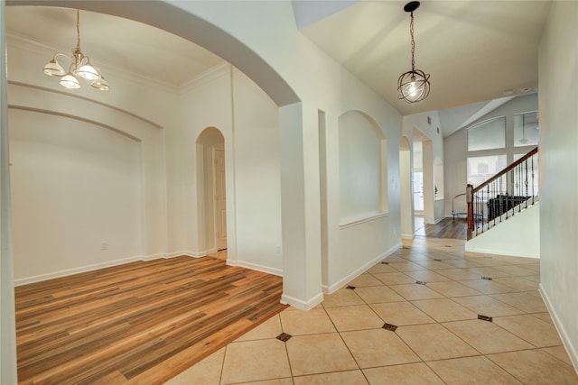 foyer with light wood-type flooring, crown molding, and an inviting chandelier