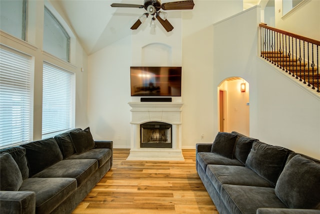 living room with light wood-type flooring, high vaulted ceiling, and ceiling fan