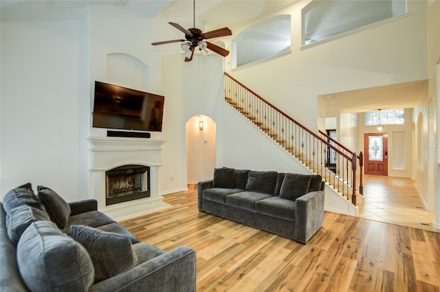 living room featuring ceiling fan, high vaulted ceiling, and light hardwood / wood-style flooring