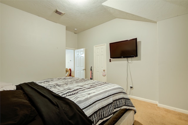 carpeted bedroom with a textured ceiling and vaulted ceiling