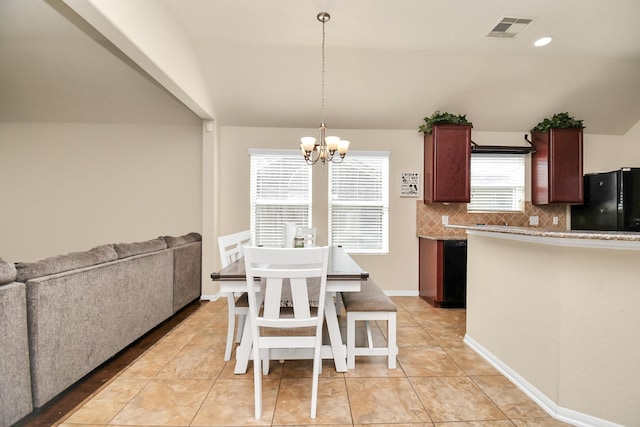 kitchen featuring tasteful backsplash, black refrigerator, plenty of natural light, and hanging light fixtures