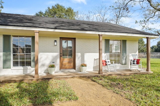 doorway to property with covered porch and a yard