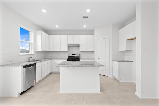 kitchen featuring light stone countertops, white cabinetry, appliances with stainless steel finishes, and a center island