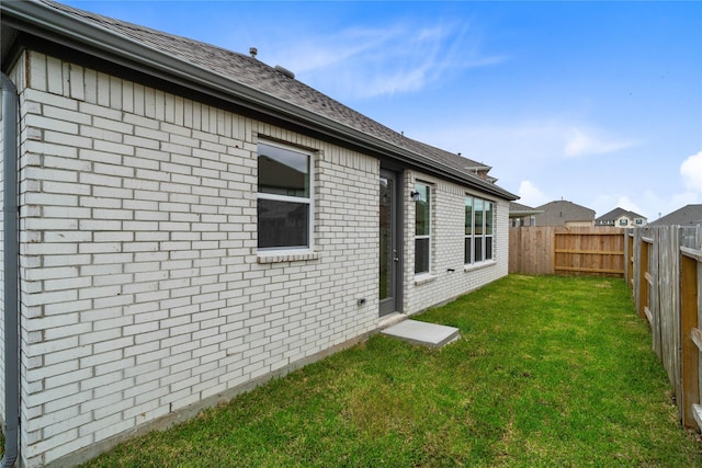 exterior space featuring brick siding, a lawn, and a fenced backyard