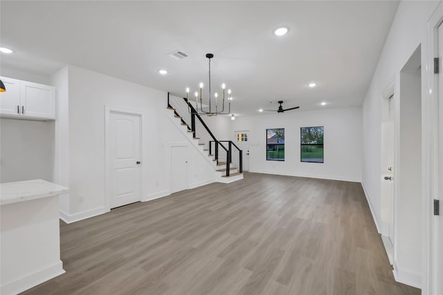 unfurnished living room with light hardwood / wood-style floors and ceiling fan with notable chandelier