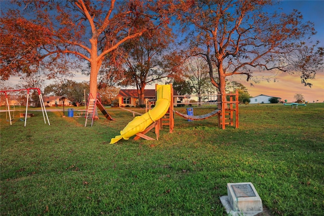 playground at dusk featuring a lawn