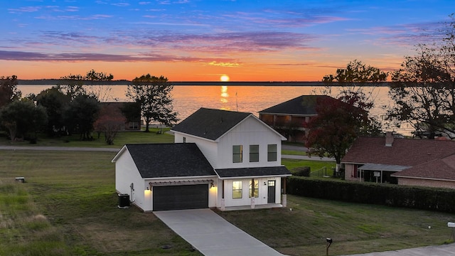 view of front facade with a water view, central AC, a garage, and a lawn