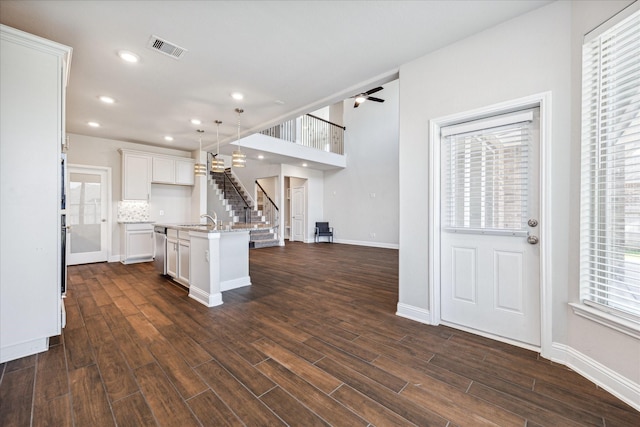 kitchen featuring pendant lighting, backsplash, ceiling fan, an island with sink, and dark hardwood / wood-style flooring