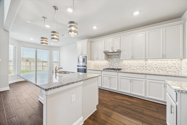 kitchen featuring decorative light fixtures, dark hardwood / wood-style flooring, a center island with sink, and white cabinetry