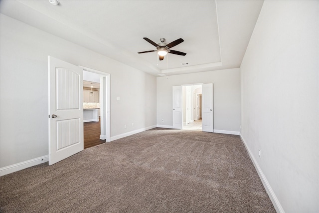 carpeted empty room featuring ceiling fan and a tray ceiling