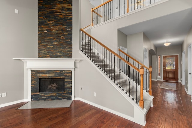 unfurnished living room with a fireplace, a towering ceiling, and wood-type flooring