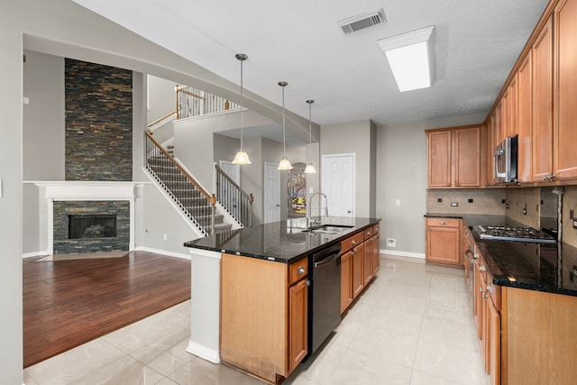 kitchen featuring a kitchen island with sink, sink, dark stone countertops, light hardwood / wood-style floors, and stainless steel appliances