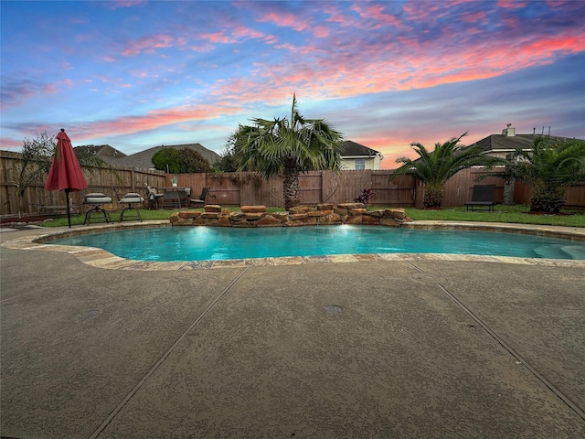 pool at dusk with pool water feature and a patio