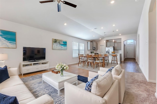 living room featuring ceiling fan, light hardwood / wood-style flooring, and vaulted ceiling