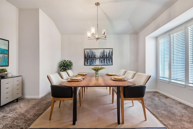 carpeted dining space with lofted ceiling, a healthy amount of sunlight, and a notable chandelier