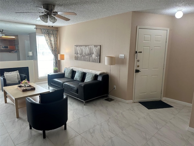 living room featuring ceiling fan and a textured ceiling