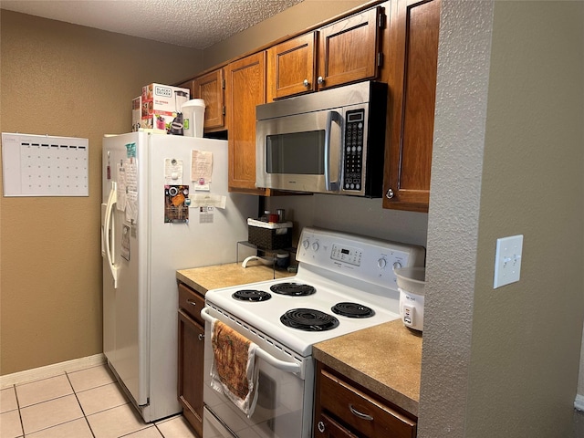 kitchen featuring a textured ceiling, white electric stove, and light tile patterned flooring