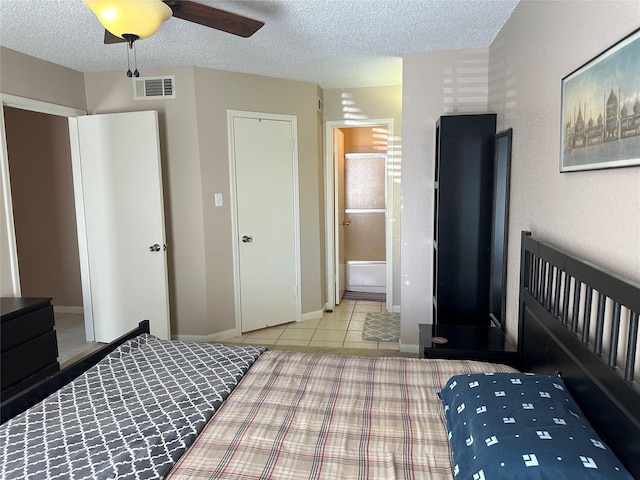 bedroom featuring ensuite bathroom, ceiling fan, light tile patterned floors, and a textured ceiling