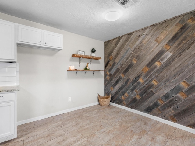 unfurnished dining area featuring a textured ceiling and wooden walls