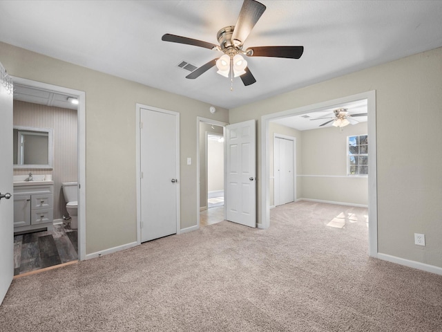 unfurnished bedroom with ceiling fan, sink, light colored carpet, and ensuite bathroom