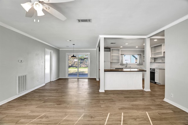 unfurnished living room featuring light hardwood / wood-style floors, ceiling fan, crown molding, and sink