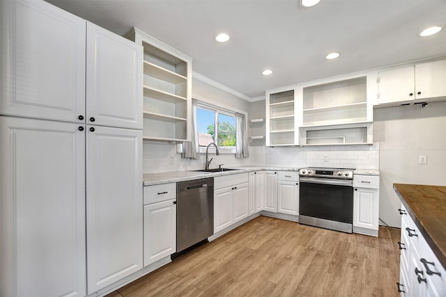 kitchen featuring appliances with stainless steel finishes, crown molding, sink, white cabinets, and butcher block counters