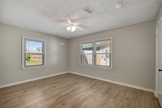 spare room with a textured ceiling, light hardwood / wood-style flooring, and plenty of natural light