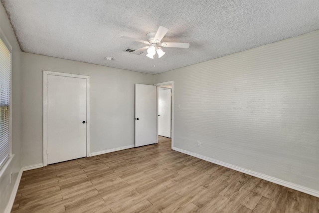 unfurnished bedroom featuring ceiling fan, light hardwood / wood-style floors, and a textured ceiling